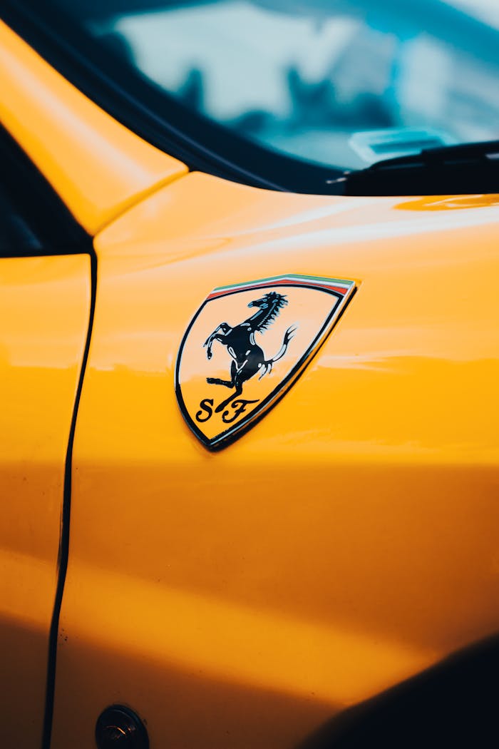 Detailed close-up of a Ferrari logo on a vibrant yellow car's body.